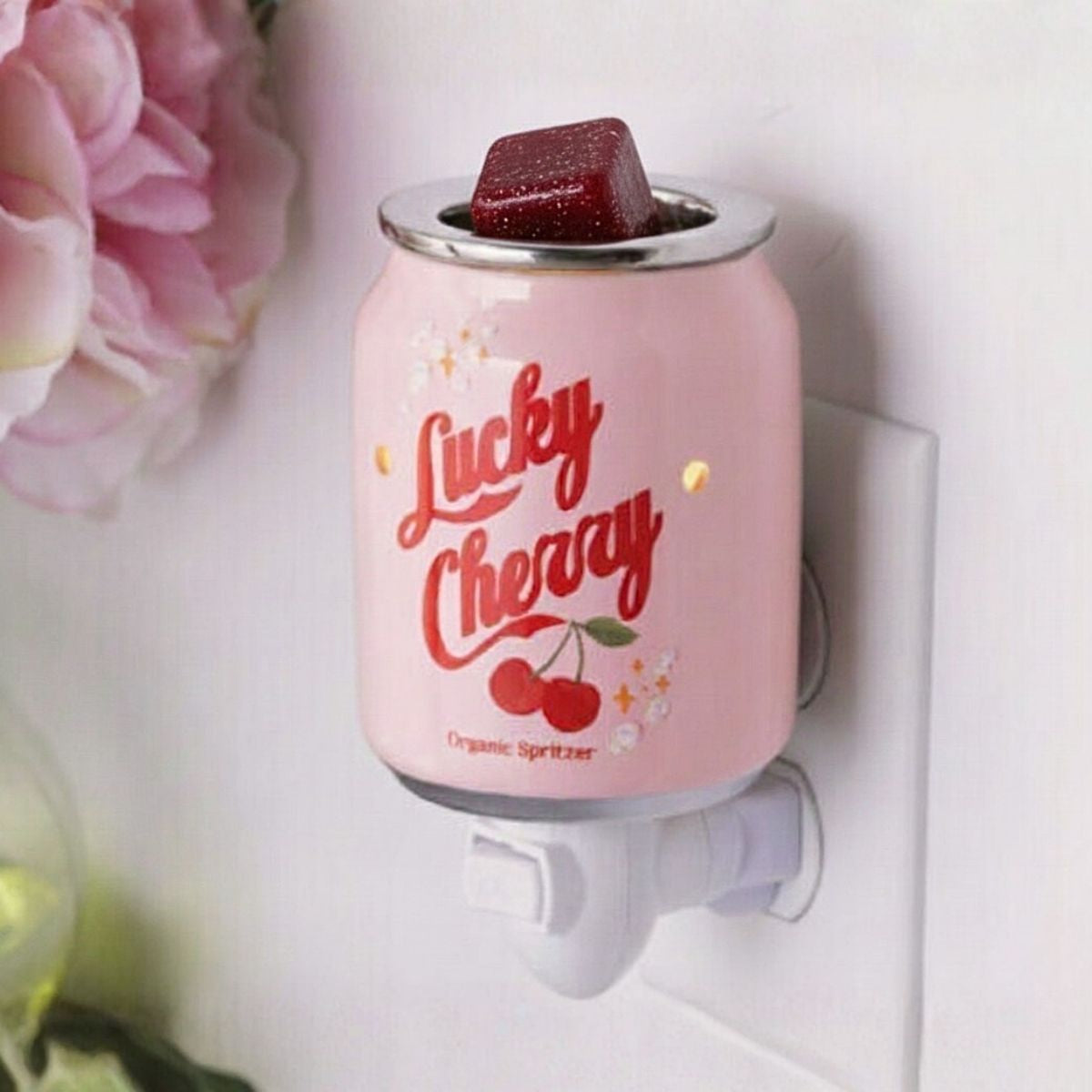 A black cherry wax melt in a pink plug in wax warmer that says Lucky Cherry.
