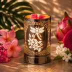 Wax warmer with a dragonf fly floral design surrounded by flowers on a wooden surface
