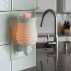 A Bubble Gum wax melt cube in a white plug in warmer. Styled in a kitchen