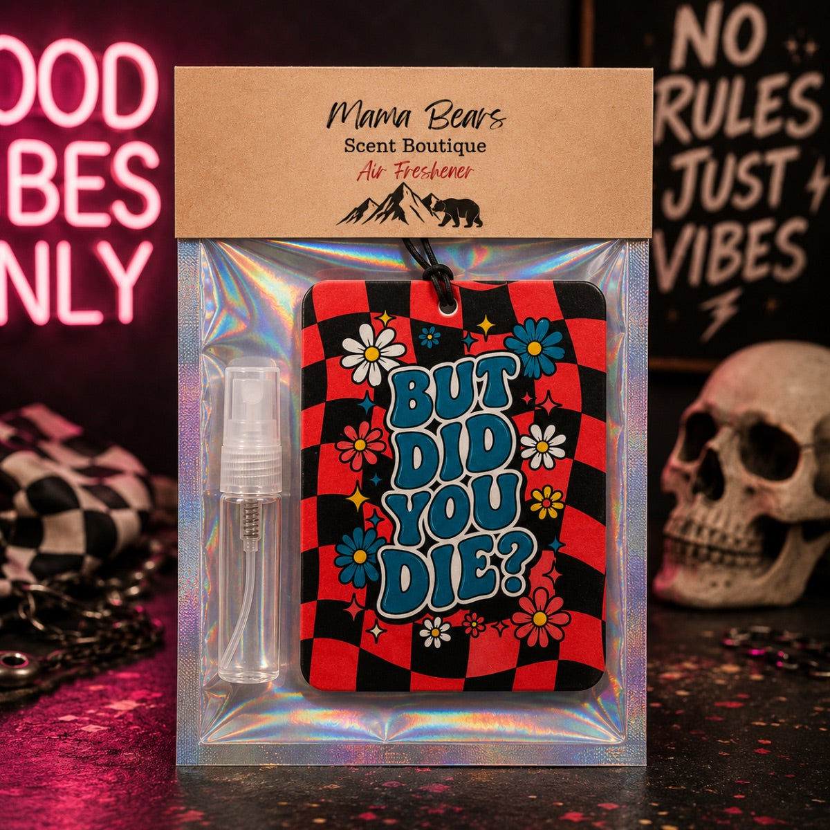 Mmma Bears Scent Boutique air freshener gift set in a clear holographic plastic bag with a kraft paper header card. The set includes a small clear spray bottle and a rectangular air freshener card featuring a red and black checkered pattern, blue text reading 'BUT DID YOU DIE?', and colorful cartoon flowers.