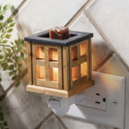 Wooden wax melt warmer illuminated and attached to an electrical outlet.