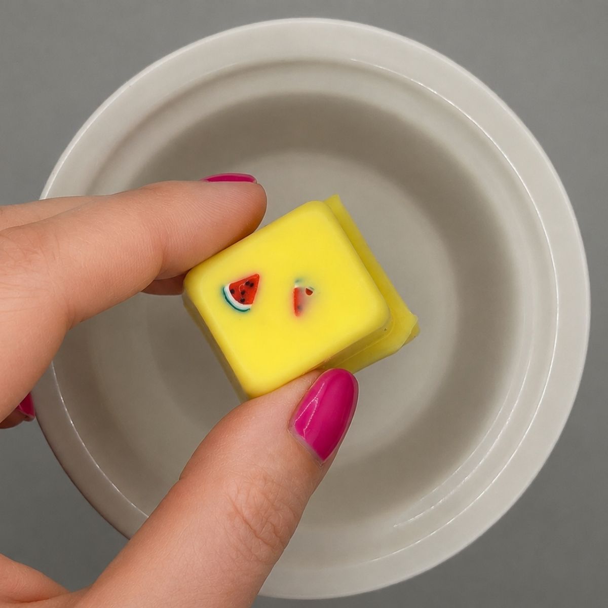 Hand holding watermelon lemonade wax melts over a wax warmer dish.