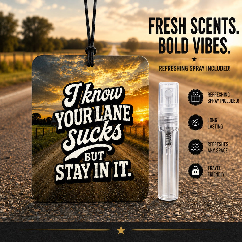 A square car air freshener hanging tag with a black cord, featuring the text 'I know YOUR LANE Sucks BUT STAY IN IT.' over a sunset road scene.