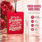 Pink air freshener with motivational quote and refreshing spray on a reflective surface with flowers in the background