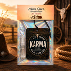 Mama Bear's Scent Boutique Air Freshener package featuring a dark wood-grain 'Karma' air freshener tag with a cow skull graphic, a small clear spray bottle, and an iridescent holographic backing card, set against a rustic western-themed background.