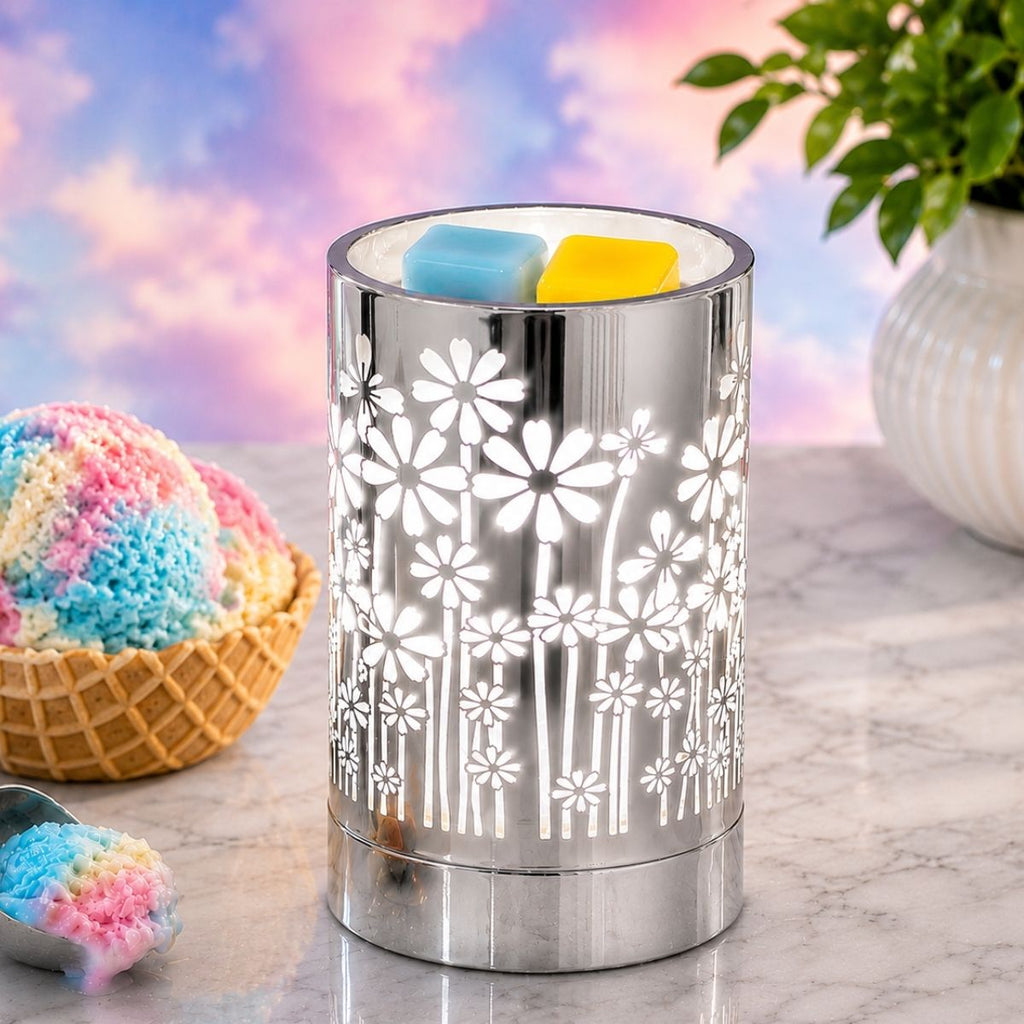 Decorative wax warmer with floral pattern on a marble surface with colorful ice cream and plant in the background.