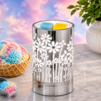 Decorative wax warmer with floral pattern on a marble surface with colorful ice cream and plant in the background.
