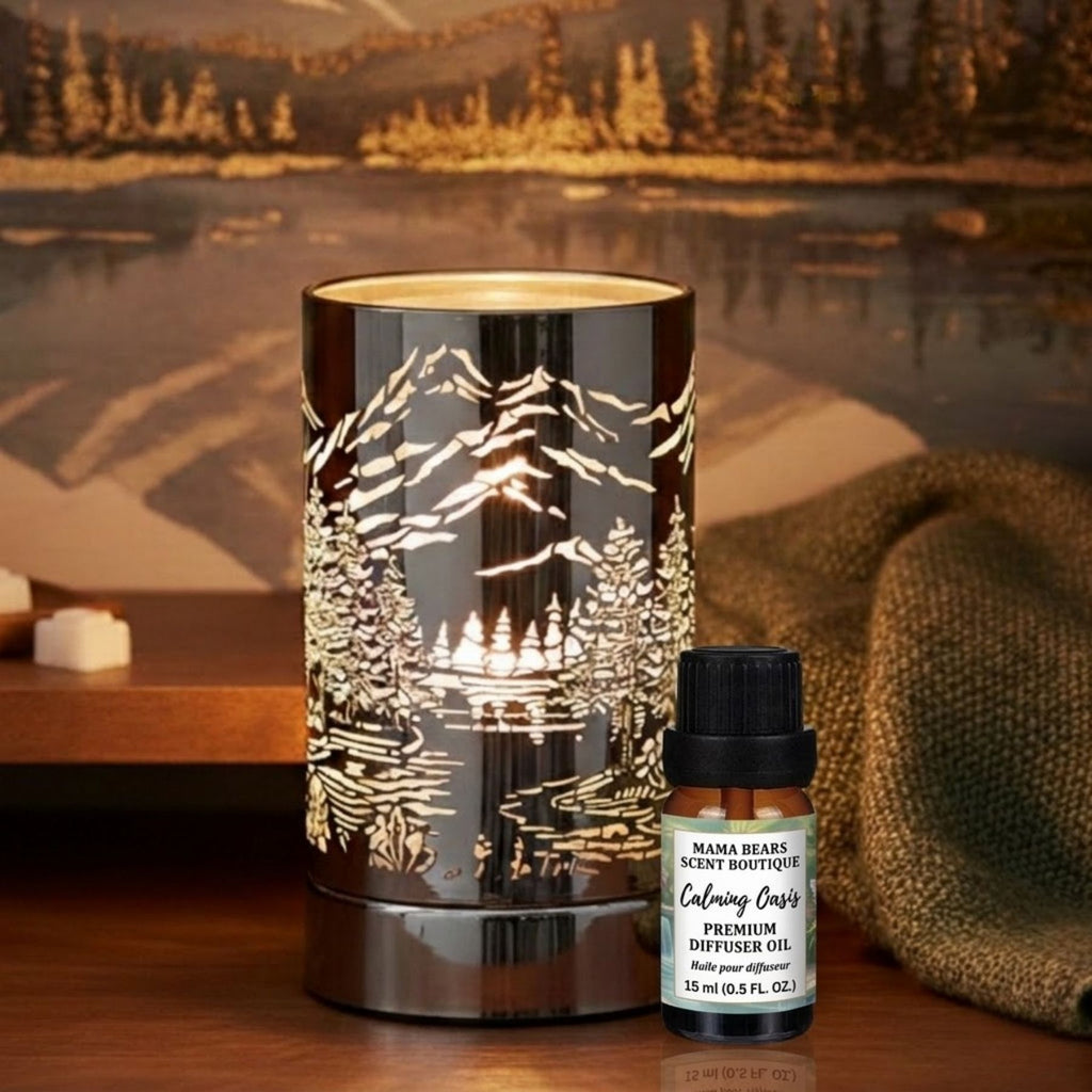 Diffuser oil/wax warmer with mountain design and a bottle of Calming Oasis diffuser oil on a wooden surface with a scenic background.