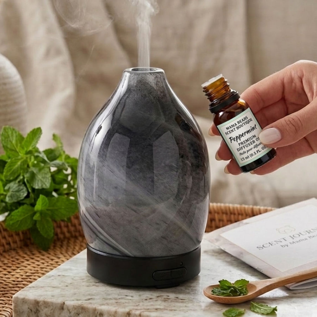 Marble-patterned diffuser with steam rising, hand holding peppermint essential oil bottle, plant and book in background