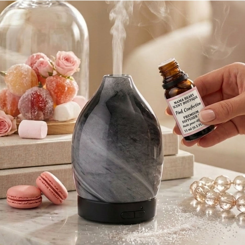 Marble-patterned diffuser with a hand holding a bottle labeled Pink Confection Diffuser Oil on a decorative surface.