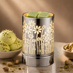 Decorative wax warmer with floral design on a table with pistachio-themed items.