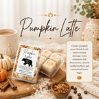 Pumpkin Latte scented wax melts by Mama Bear Scent Boutique, shown in a clear plastic clamshell package with several cream-colored wax cubes inside. The product is styled on a wooden board with autumn ingredients like cinnamon sticks, brown sugar, coffee beans, and a small pumpkin, next to a mug and a cozy knit blanket.