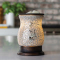 Mosaic-patterned candle warmer on a surface with a blurred background