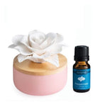 Pink diffuser with white porcelain flower on top and a bottle of  peppermint essential oil.