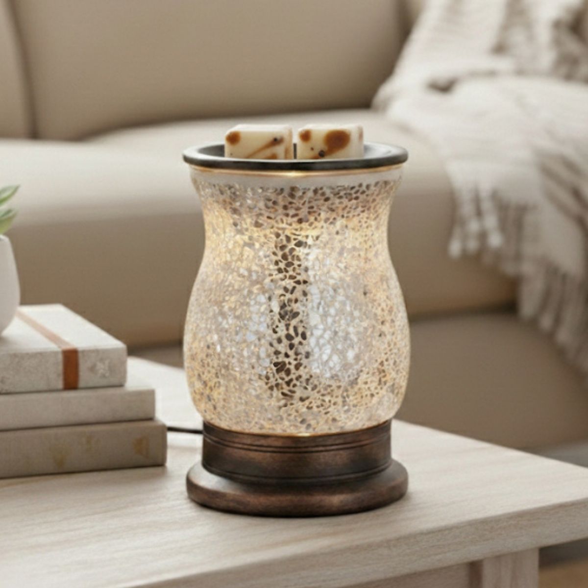 Mosaic-patterned candle warmer with Spice Mocha Latte wax melt cubes in it on a coffee table with books and a blanket in the background
